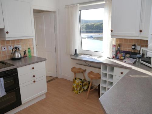 a kitchen with white cabinets and a window with a view of the ocean at The Bridge in Kippford