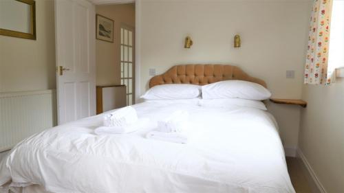a large white bed with two white towels on it at The Bridge in Kippford