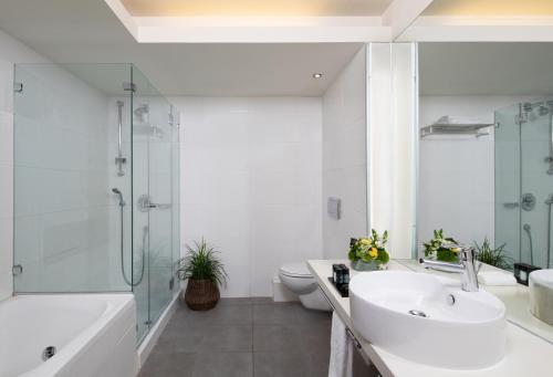 a bathroom with a sink and a shower and a toilet at Neptune Eilat By Dan Hotels in Eilat