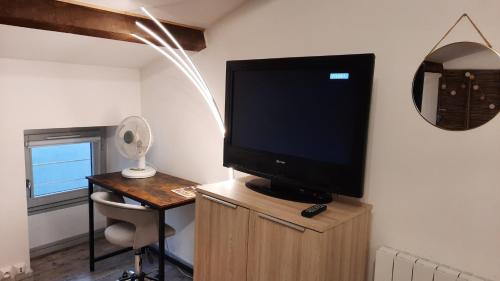 a television on a wooden stand in a room at Suite 3 pièces chambre+cuisine+SDB centre ville in Privas