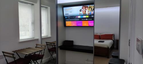 a room with a television on a wall with a bedroom at Birds Nest - Surrey Quays in London