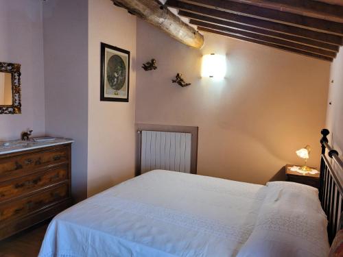 a bedroom with a white bed and a dresser at Casa Lucia in Monticiano