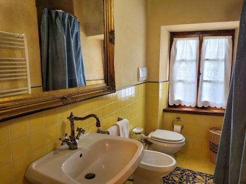 a bathroom with a sink and a toilet and a mirror at Casa Lucia in Monticiano