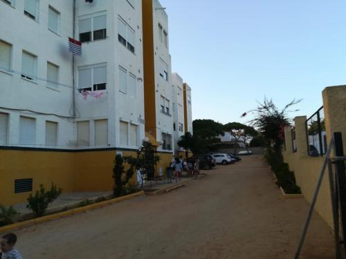 eine Gruppe von Menschen, die eine Straße entlang gehen, neben einem Gebäude in der Unterkunft El Vigía Beach. Mazagón in Mazagón