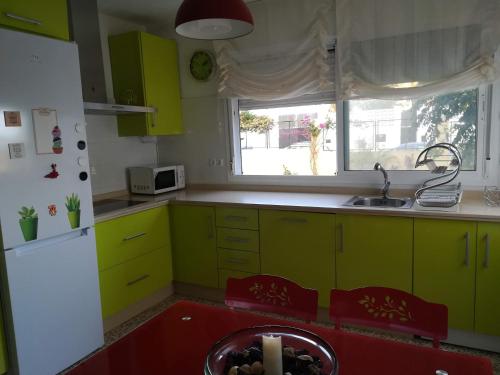 uma cozinha com armários verdes, um lavatório e uma janela em El Vigía Beach. Mazagón em Mazagón