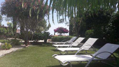 a row of white chairs sitting on the grass at Latchi Aria villa in Neo Chorio