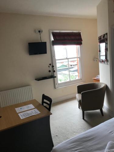 a room with a desk and a chair and a window at The Harp Freehouse and Guesthouse in Ipswich