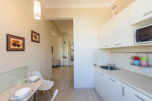 a kitchen with white cabinets and a table with chairs at Однокімнатні апартаменти на Майдані, дистанційне заселення 24х7 in Kyiv