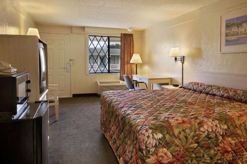 a hotel room with a large bed and a window at Super 8 by Wyndham Lantana West Palm Beach in Lantana