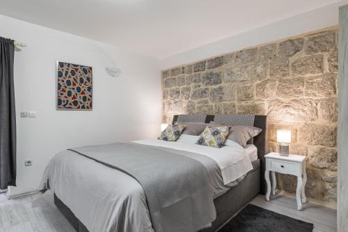 a bedroom with a large bed with a stone wall at Studio Toniko in Split