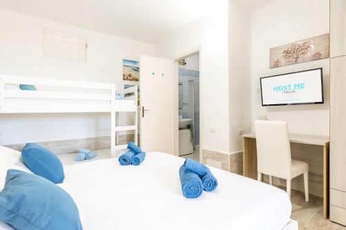 1 Schlafzimmer mit 2 Betten mit blauen Kissen und einem Schreibtisch in der Unterkunft Free Beach House - 50 mt from the beach in Costa Rei