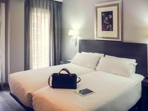 a hotel room with a bed with a bag on it at Mercure Madrid Centro in Madrid