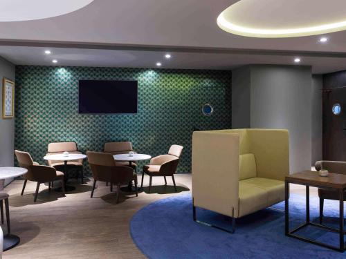 a waiting room with tables and chairs and a flat screen tv at Mercure Madrid Centro in Madrid