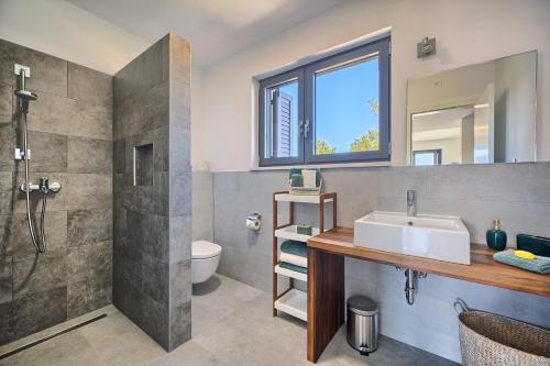 La salle de bains est pourvue d'un lavabo et d'une douche. dans l'établissement Villa Ming - pool, sea-view and peace, à Slatine