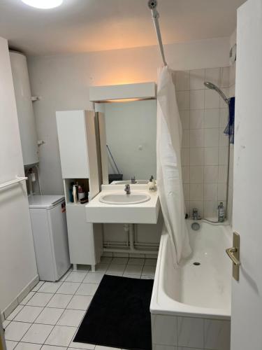 a white bathroom with a sink and a tub at Grand appartement lumineux in Noisy-le-Grand