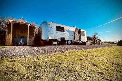 un rimorchio è parcheggiato accanto a un capannone di WildView Cosy Glamping with Outdoor Bath and stunning scenery a Helston