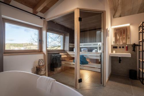 a bathroom with a tub and a large window at Forstgut Luxuschalets in Regen