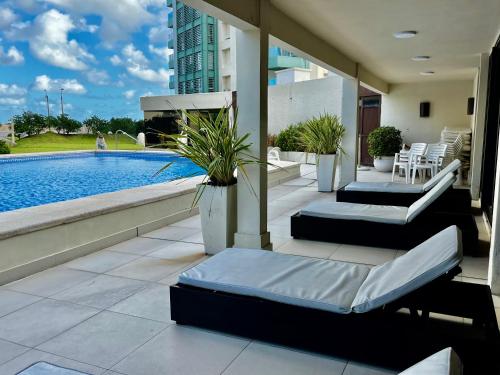 a patio with a pool and chairs and a building at Depto FRENTE al MAR la mejor ubicación Parada 3 brava INIGUALABLE cochera gym sala de juegos parrilleros imperdible in Punta del Este