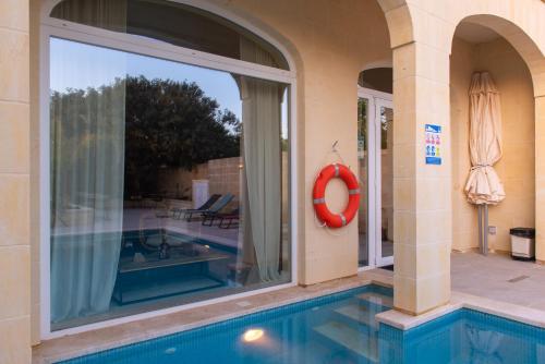 a swimming pool with a red life preserver next to a building at The Carob Tree in Victoria
