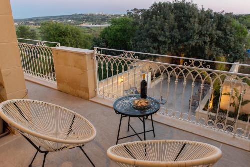 a balcony with two chairs and a table with a bottle of wine at The Carob Tree in Victoria