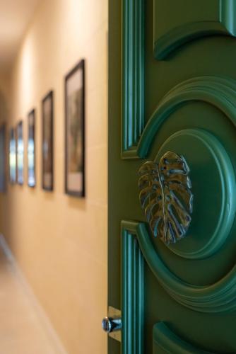 a butterfly door knocker on a green wall with pictures at The Carob Tree in Victoria