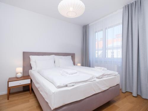 a white bedroom with a large bed and a window at MyFavorit Apartments - Spacious Apartments next to Puplic Transport U1 direct connection to Citycenter in Vienna