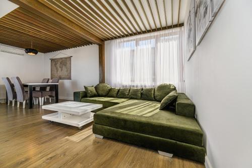 een woonkamer met een groene bank en een tafel bij KOA - Memo Haus in Braşov