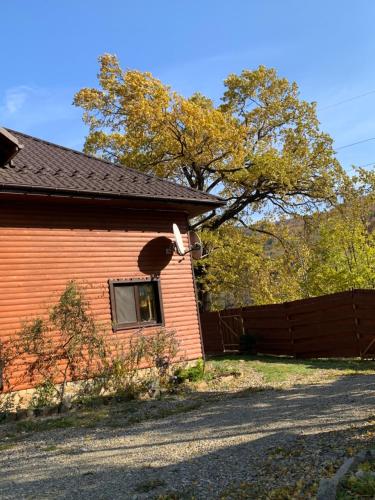 a red brick house with a window and a fence at Guest House Pid Dubom Карпати Під Дубом in Skole