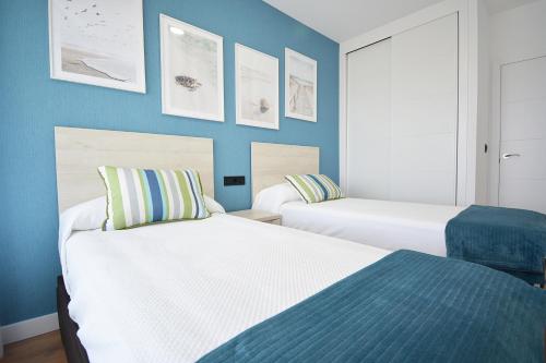 two beds in a room with blue walls at Precioso apartamento con piscina en Sanxenxo in Sanxenxo