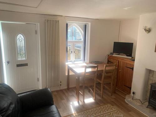 Una sala de estar con una mesa y una ventana. en Cozy Cottage 18th Century Seaside Escape Free parking, en Weymouth