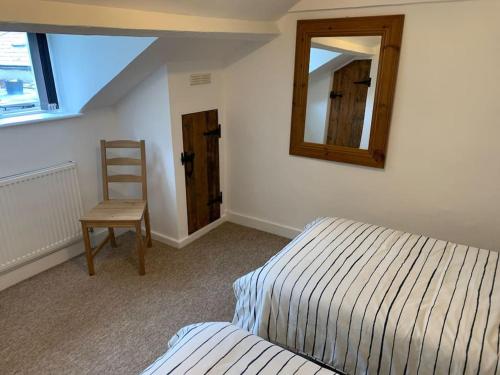 a bedroom with a bed and a chair and a mirror at Cozy Cottage 18th Century Seaside Escape Free parking in Weymouth