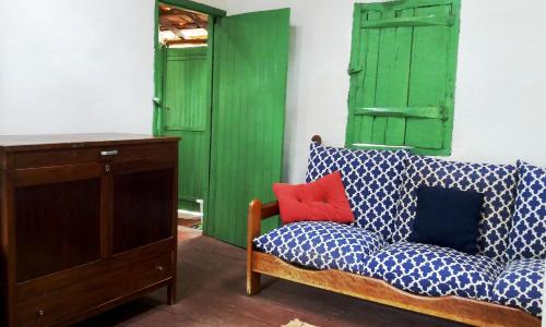 een woonkamer met een bank en groene deuren bij Simplicidade - Uma autêntica casa de roça mineira in Delfim Moreira
