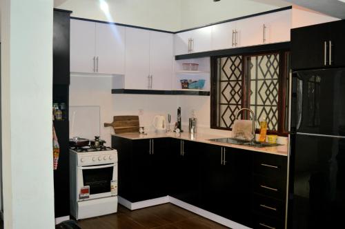 a kitchen with white cabinets and a black and white stove at Bujumbura Sweet Home - Maison bien équipée avec voiture gratuite in Bujumbura