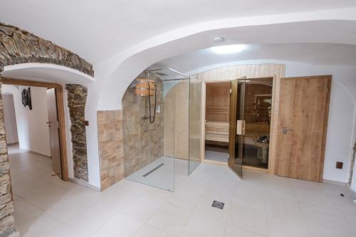 baño con ducha de cristal y pared de piedra. en Penzion U Fořta, en Rožmberk nad Vltavou
