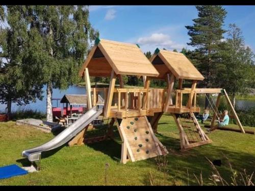 a wooden playground with a slide and a play structure at Holiday Home Rödvattnet in Rödvattnet