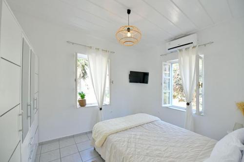 a white bedroom with a bed and windows at Olivo II Luxury Apartment in Hydra