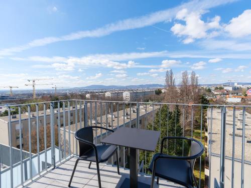 a balcony with two chairs and a table on a building at MyFavorit Apartments - Spacious Apartments next to Puplic Transport U1 direct connection to Citycenter in Vienna