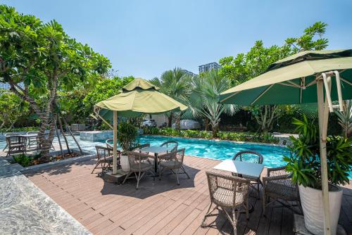 un patio con mesas y sombrillas junto a una piscina en Cozrum Homes - Sonata Residence en Ho Chi Minh