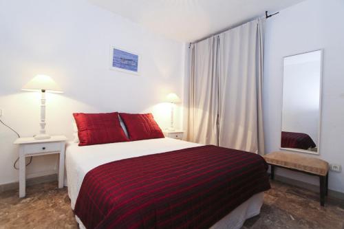 サロウにあるBAHIA II HomeStay by Turismarのベッドルーム1室(赤い枕と鏡付きのベッド1台付)