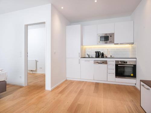 a white kitchen with white cabinets and a wooden floor at MyFavorit Apartments - Spacious Apartments next to Puplic Transport U1 direct connection to Citycenter in Vienna