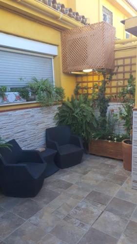 a patio with blue chairs and plants in front of a building at La Baraka de Guadalmar B&B Aeropuerto in Málaga