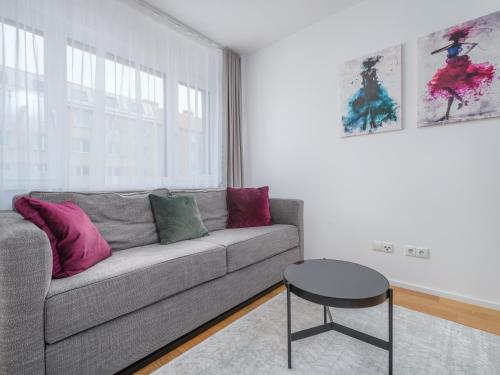 a living room with a gray couch and pink pillows at MyFavorit Apartments - Spacious Apartments next to Puplic Transport U1 direct connection to Citycenter in Vienna