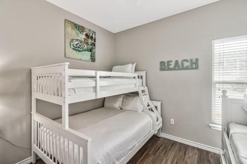 a white bedroom with a bunk bed and a ladder at Chillin' Channelside in Padre Island