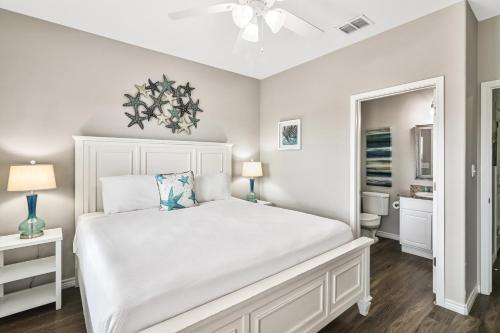 a bedroom with a white bed and a bathroom at Chillin' Channelside in Padre Island