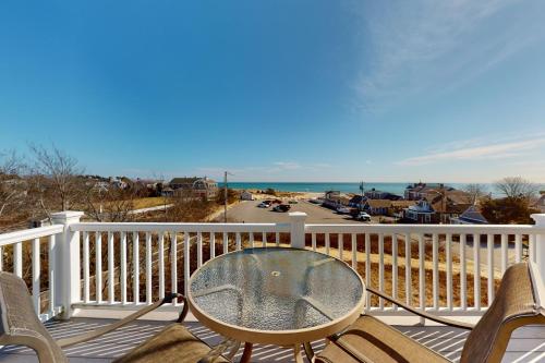 a table and chairs on a deck with a view of a street at Seashells on Bank in Harwich Port