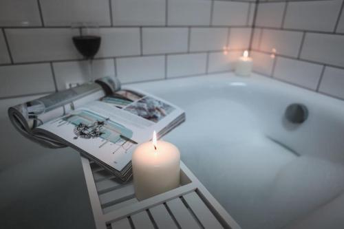 a candle sitting on a shelf next to a bath tub at Beach Lovers Paradise in Portreath - With Sea Views & Log Burner just 100m from beach in Portreath