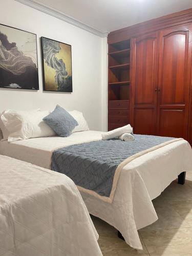 a bedroom with two beds and a wooden cabinet at Hospedaje él Familia in Cartagena de Indias