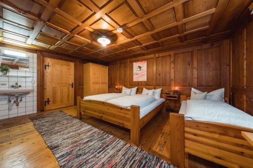 two beds in a room with wooden walls and wooden floors at Ferienhaus Helga in Sankt Gallenkirch