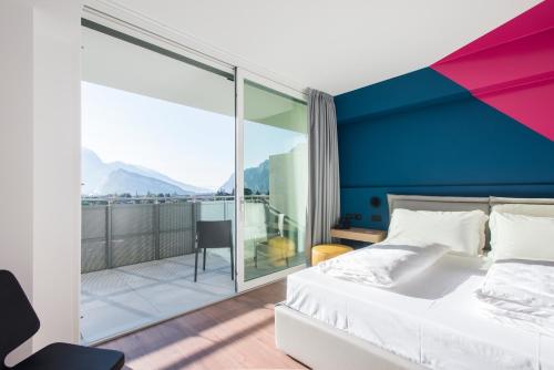 ein Schlafzimmer mit einem großen Bett und einem Balkon in der Unterkunft HOODY ACTIVE & HAPPINESS HOTEL in Arco