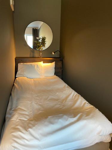 a bed with white sheets and a mirror in a room at Magnolia House Norrviken in Sollentuna